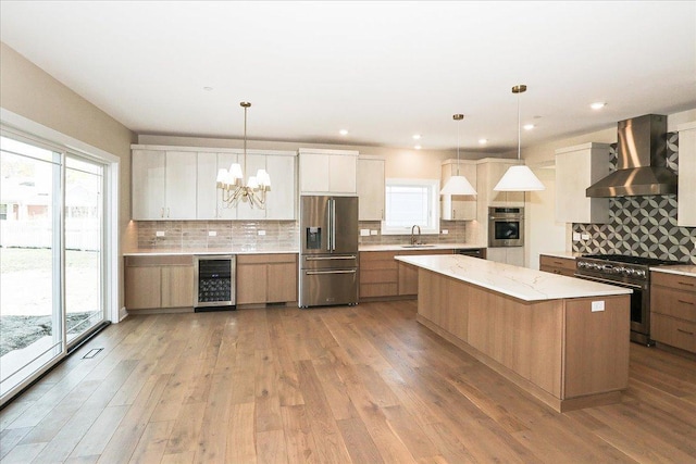 kitchen featuring beverage cooler, appliances with stainless steel finishes, a sink, a notable chandelier, and wall chimney exhaust hood