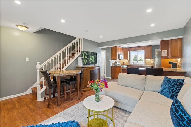 living room featuring recessed lighting, light wood-style flooring, baseboards, and stairs