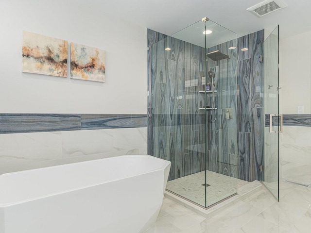 bathroom with visible vents, a marble finish shower, tile walls, a freestanding bath, and marble finish floor