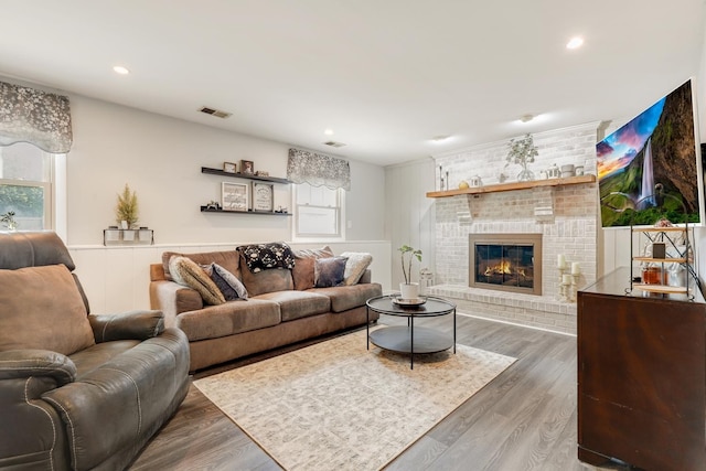 living area with a fireplace, recessed lighting, wood finished floors, and visible vents