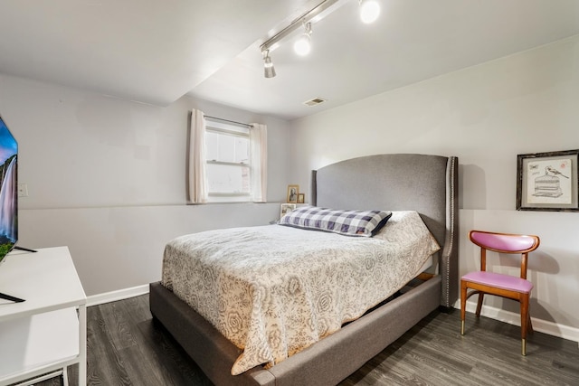 bedroom featuring baseboards, dark wood finished floors, visible vents, and track lighting