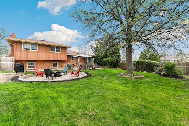 back of house with a fire pit, a fenced backyard, a chimney, brick siding, and a gazebo