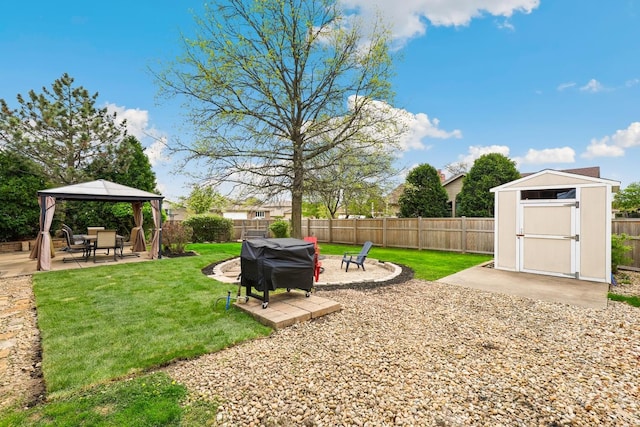 view of yard featuring an outdoor structure, a fenced backyard, a patio area, a gazebo, and a storage shed