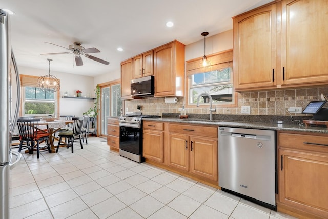 kitchen with ceiling fan, hanging light fixtures, appliances with stainless steel finishes, a sink, and backsplash