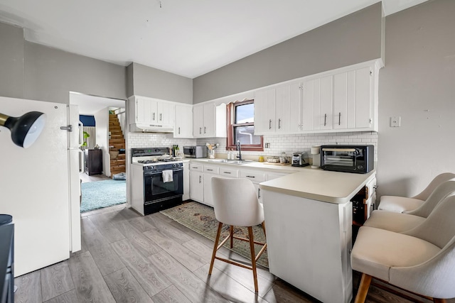 13134 S Burley Ave, Chicago, IL 60633 - kitchen featuring a sink, light wood-type flooring, a peninsula, gas stove, and freestanding refrigerator