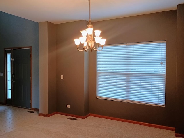 unfurnished room featuring baseboards, visible vents, an inviting chandelier, and carpet