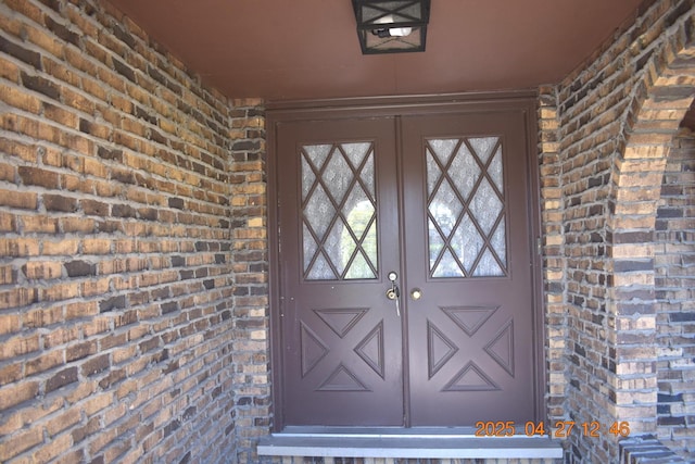 view of exterior entry with brick siding and french doors