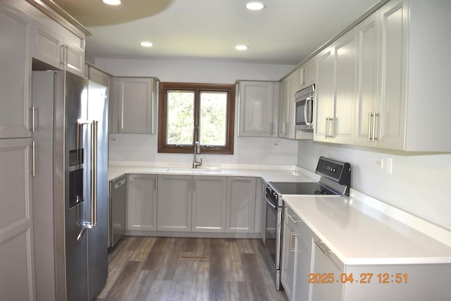 kitchen with dark wood-style flooring, recessed lighting, light countertops, a sink, and stainless steel appliances
