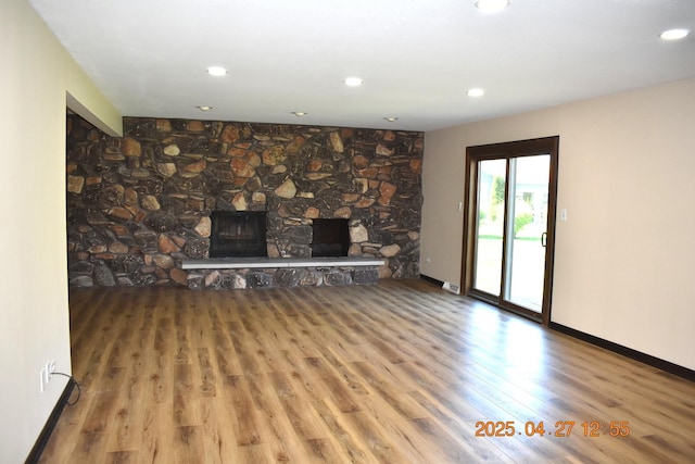 unfurnished living room featuring recessed lighting, baseboards, wood finished floors, and a fireplace