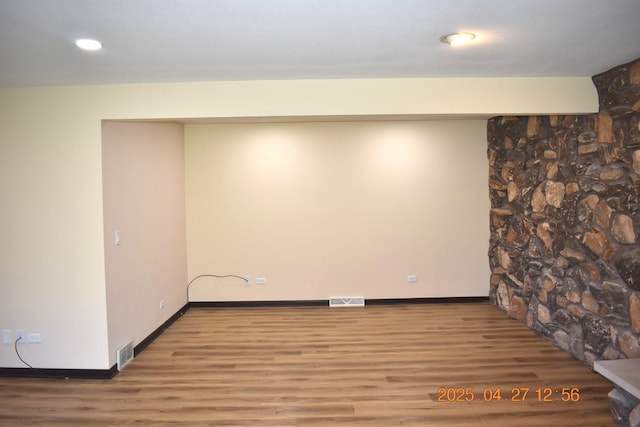 finished below grade area featuring baseboards, visible vents, and wood finished floors