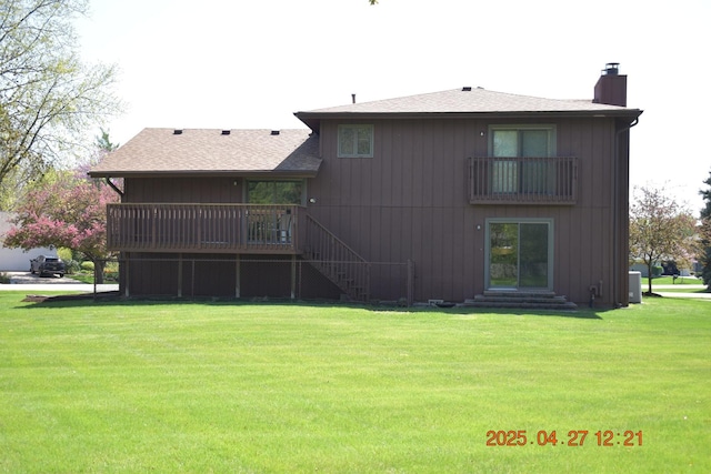 back of house with entry steps, a chimney, and a yard
