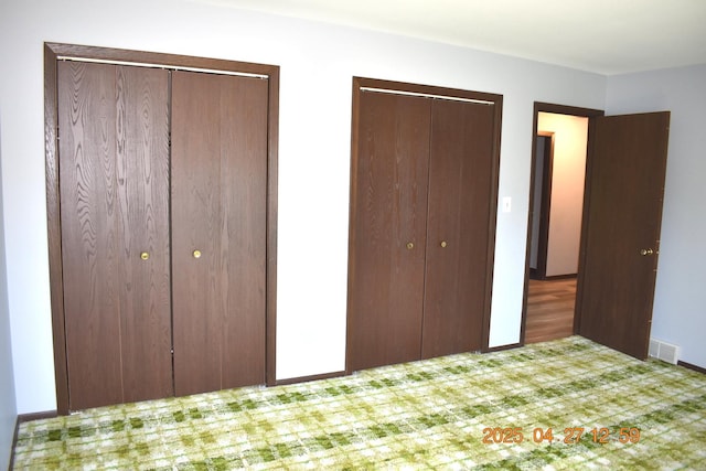 unfurnished bedroom with visible vents, multiple closets, carpet floors, and baseboards