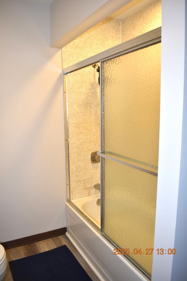 full bathroom featuring toilet, baseboards, enclosed tub / shower combo, and wood finished floors