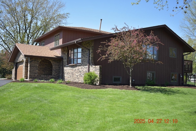 view of side of home with a lawn, an attached garage, and stone siding