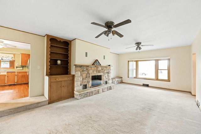 unfurnished living room with ceiling fan, healthy amount of natural light, and light colored carpet