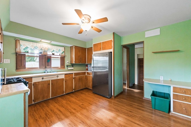 kitchen featuring freestanding refrigerator, a ceiling fan, light countertops, brown cabinetry, and light wood finished floors