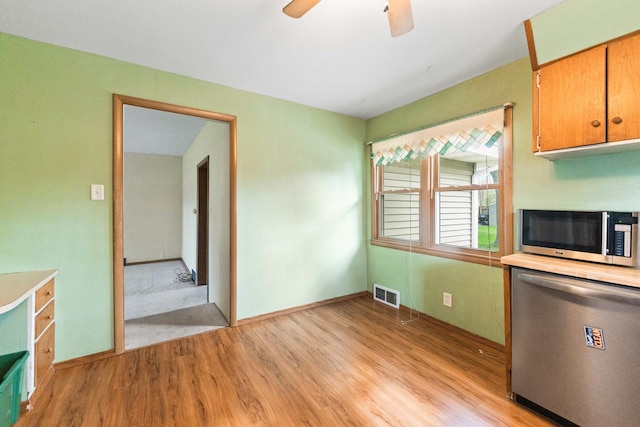 unfurnished dining area with light wood-style flooring, a ceiling fan, and baseboards