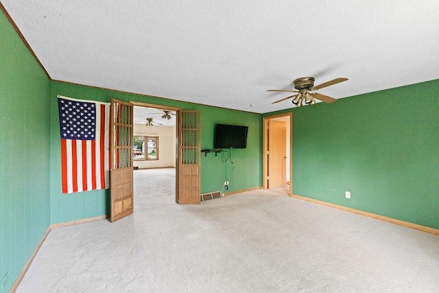 unfurnished living room featuring a ceiling fan, baseboards, a textured ceiling, and carpet flooring