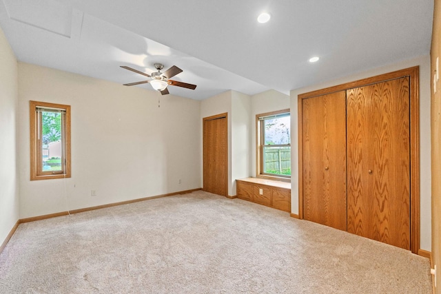 unfurnished bedroom with multiple closets, carpet, multiple windows, baseboards, and recessed lighting