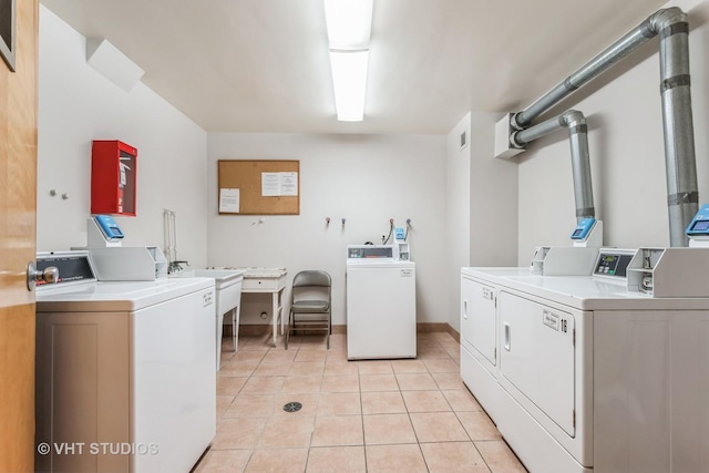 shared laundry area with light tile patterned floors, separate washer and dryer, and baseboards