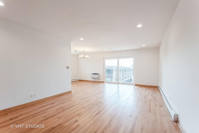 unfurnished living room featuring an AC wall unit, a notable chandelier, baseboard heating, and light wood-style floors
