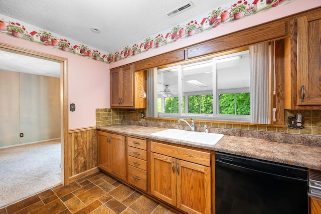 kitchen featuring visible vents, brown cabinetry, a textured ceiling, a sink, and dishwasher