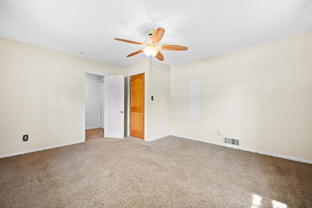 carpeted spare room featuring baseboards, ceiling fan, and visible vents
