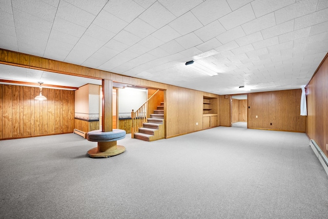 below grade area featuring stairs, baseboards, wooden walls, baseboard heating, and carpet