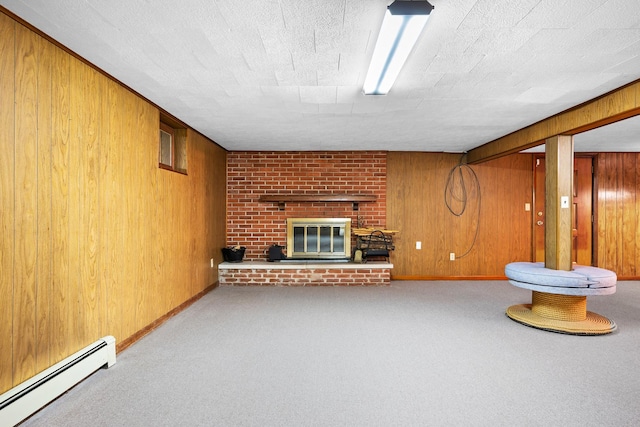 interior space with wooden walls, a baseboard heating unit, carpet flooring, and a brick fireplace