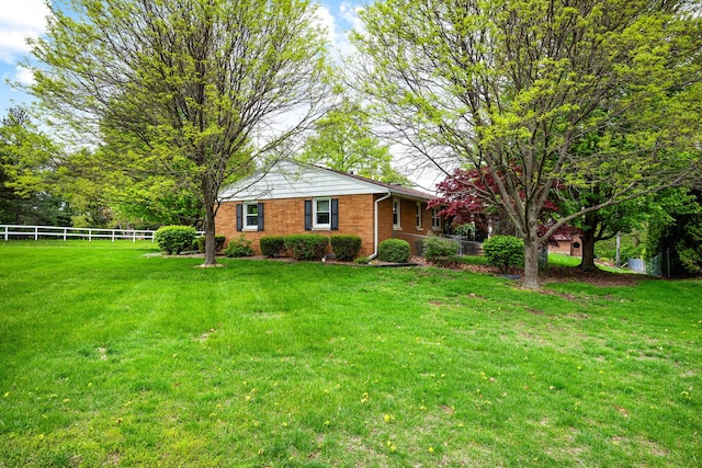 view of front of property featuring brick siding, fence, and a front yard