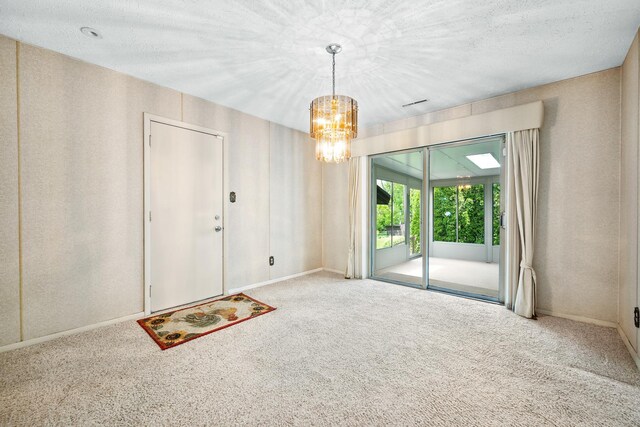 carpeted empty room with baseboards, a textured ceiling, and a notable chandelier