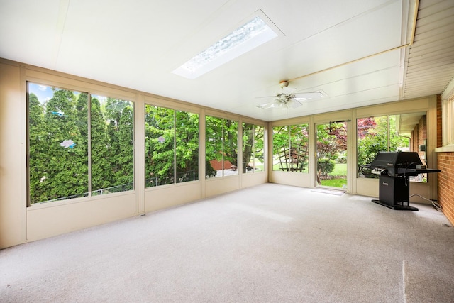 unfurnished sunroom featuring a skylight, ceiling fan, and plenty of natural light