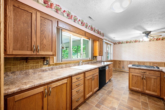kitchen featuring a sink, black dishwasher, a textured ceiling, and a healthy amount of sunlight