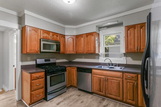 510 S Cottage Grove Ave, Urbana, IL 61802 - kitchen featuring stainless steel appliances, light wood-style flooring, a textured ceiling, dark countertops, and brown cabinetry