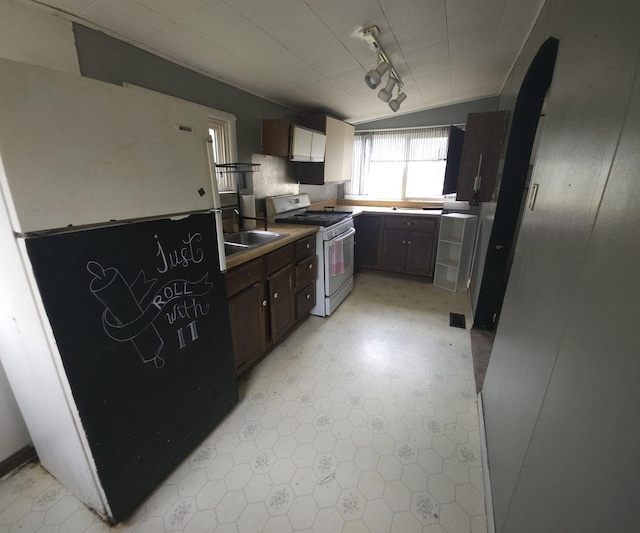 303 S Spruce St, Villa Grove, IL 61956 - kitchen featuring white range with gas stovetop, a sink, freestanding refrigerator, dark brown cabinetry, and light floors