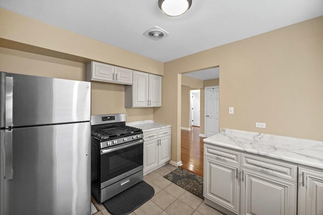 405 E 109th St Unit 203, Chicago, IL 60628 - kitchen featuring appliances with stainless steel finishes, white cabinetry, light tile patterned floors, and light stone counters