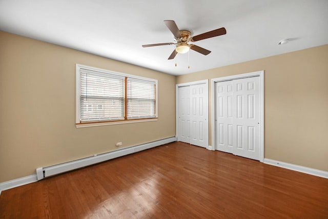 405 E 109th St Unit 203, Chicago, IL 60628 - unfurnished bedroom featuring a baseboard heating unit, multiple closets, wood finished floors, and a ceiling fan