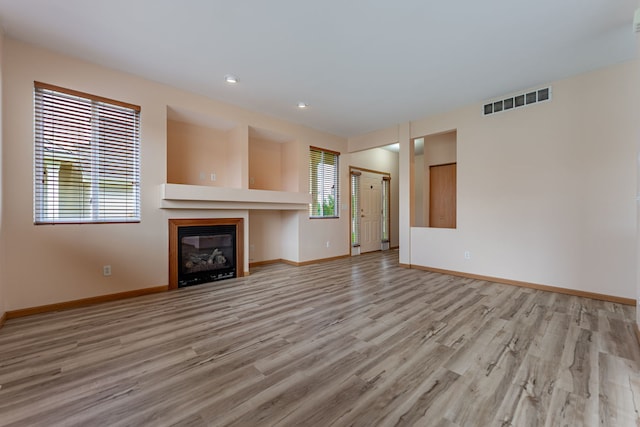 7480 Thomas Dr Unit 7480, Loves Park, IL 61111 - unfurnished living room with a glass covered fireplace, visible vents, light wood-style flooring, and baseboards
