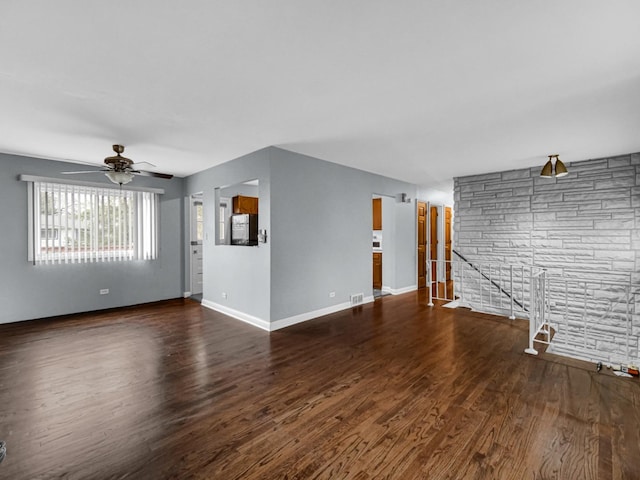 unfurnished living room featuring a ceiling fan, baseboards, visible vents, and wood finished floors