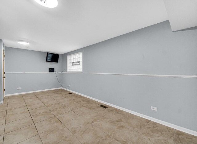 basement featuring baseboards and tile patterned flooring
