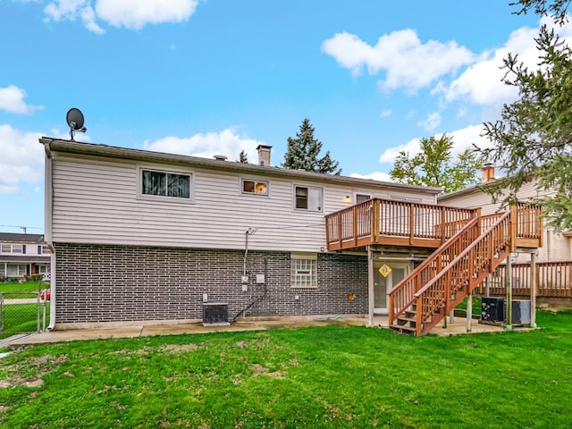 rear view of house with fence, stairs, brick siding, a wooden deck, and a lawn