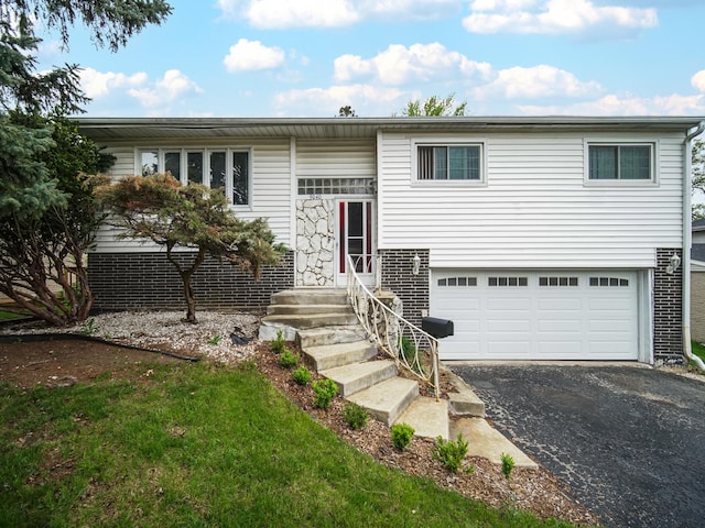 bi-level home featuring a garage and aphalt driveway