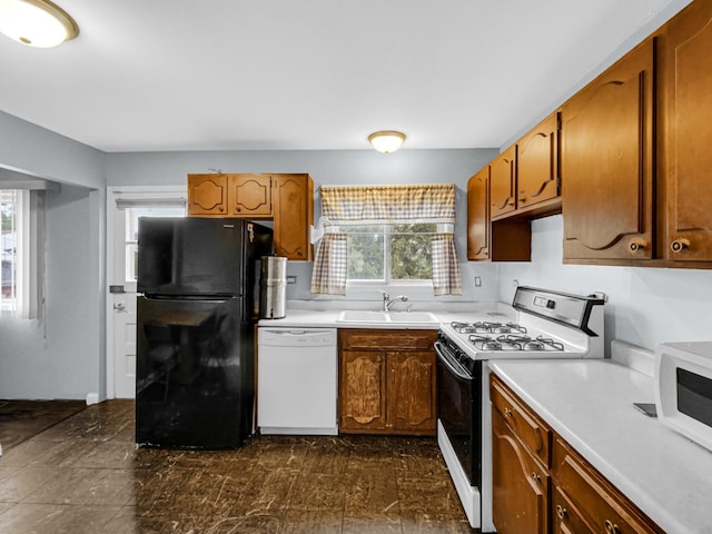 kitchen with a sink, brown cabinets, white appliances, and light countertops