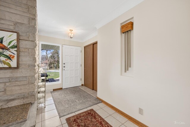 foyer entrance featuring light tile patterned flooring, ornamental molding, and baseboards