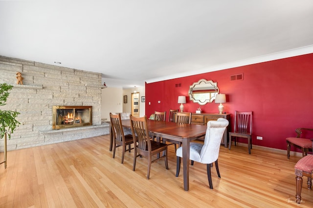 dining area with visible vents, wood finished floors, and a stone fireplace