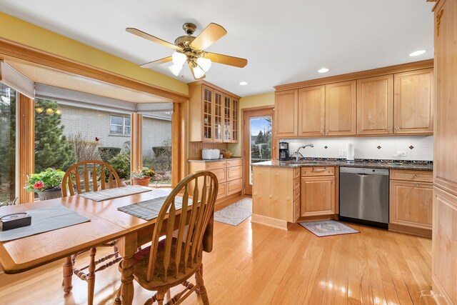kitchen with light wood-style floors, stainless steel dishwasher, glass insert cabinets, and a sink