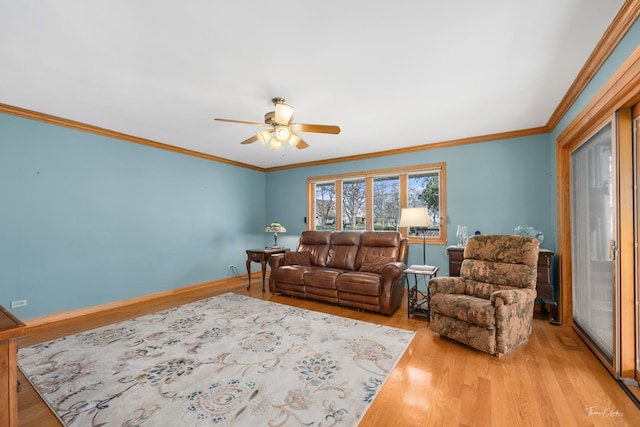 living area with baseboards, a ceiling fan, crown molding, and light wood finished floors