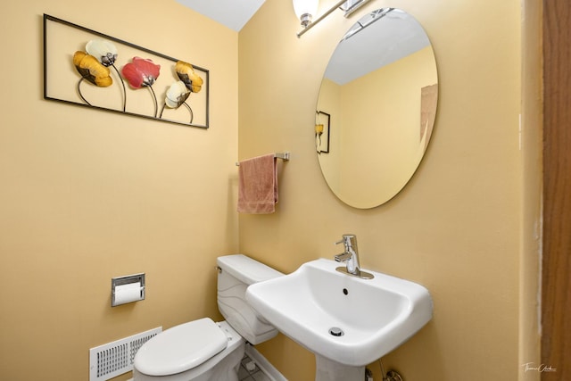 half bath featuring a sink, toilet, visible vents, and baseboards