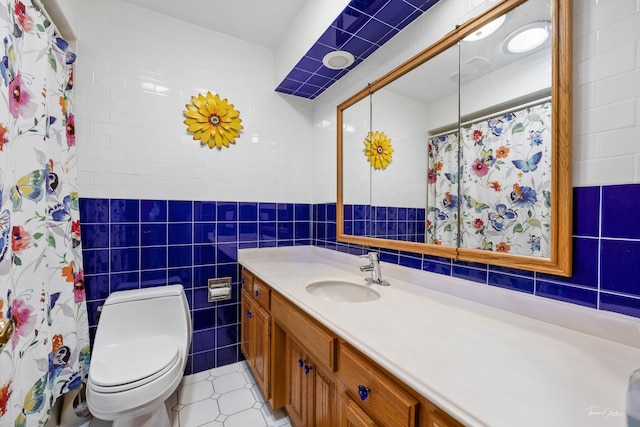 bathroom with tile patterned flooring, tile walls, a shower with shower curtain, toilet, and vanity