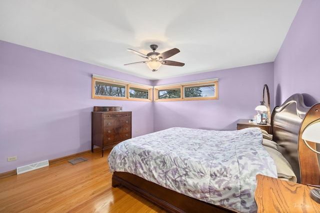 bedroom featuring light wood finished floors, visible vents, ceiling fan, and baseboards